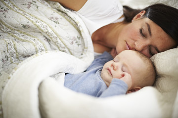 Fototapeta na wymiar Mother and baby sleeping in bed