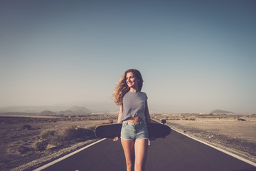 Spain, Tenerife, smiling woman with longboard standing on empty country road