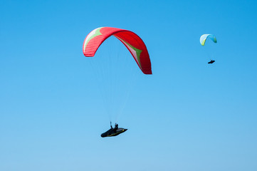 Paragliding in the sky. Two paraglider fly over the tops of the mountains in summer sunny day. Carpathians, Ukraine.
