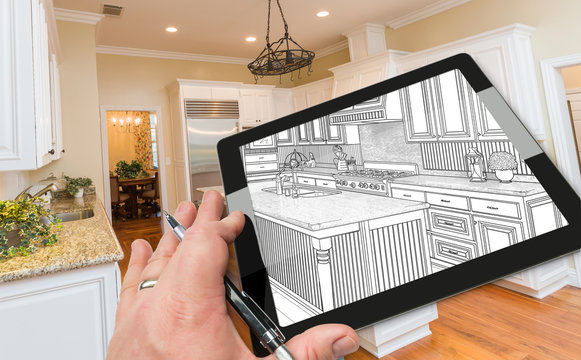 Hand of Architect on Computer Tablet Showing Drawing of Kitchen Photo Behind.