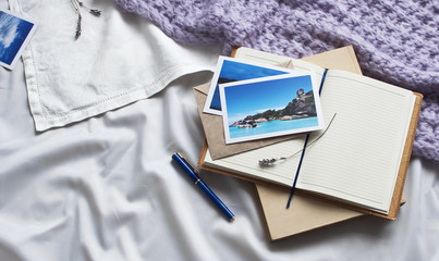 Notebook letter and book travel photographs on a white textile in bed. Diary Envelope Lifestyle...