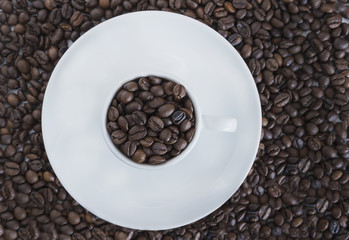 coffee concept/white cup of coffee with coffee beans on coffee beans background top view
