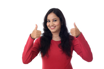 Young woman showing thumbsup gesture against white background