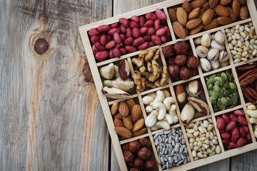 Box of nuts on a wooden table with space for text, top view