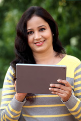 Happy young woman holding tablet computer at outdoor