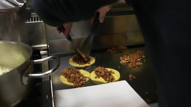 Chef cooking delicious mexican tacos in a restaurant.