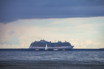 Obraz premium Cruise liner and four boats in Baltic sea at cloudy day