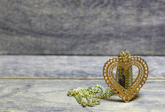 Golden heart on a chain and colored stones, minerals in the bottle on wooden background. Beautiful congratulation card background for St. Valentine`s day. Copyspace.