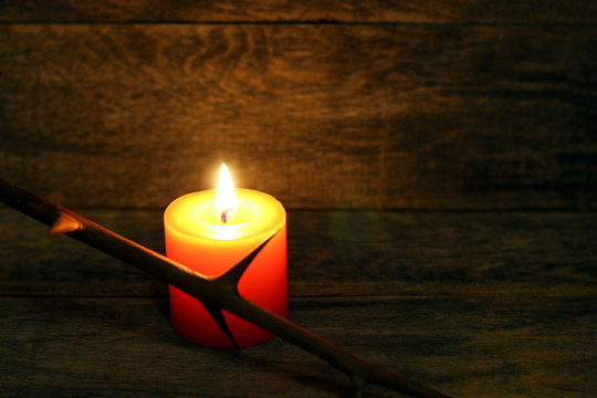 Prickly branch and burning candle on wooden background. Copyspace