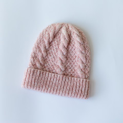 Hat and mittens connected by hand from wool on wooden background