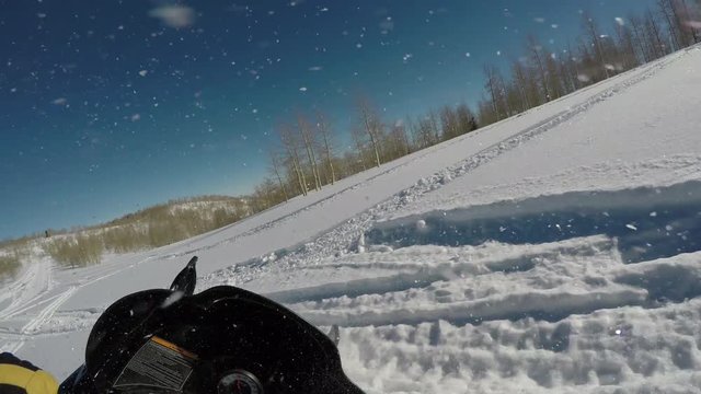 Snowmobile ride mountain snow powder turning POV. Snowmobile trail ride across high mountain meadow and forest at high speed high in central Utah in winter. Recreation and fun.