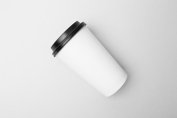 Blank white paper cup with black cover on the grey background
