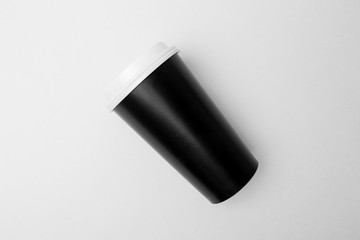 Blank black paper cup with white cover on the grey background