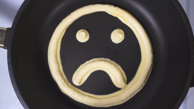 Hurt Emoticon made from butter. Accelerated Video, butter melts in a skillet.