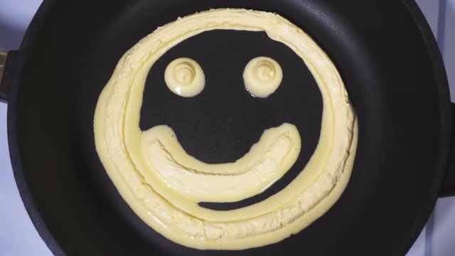 Smiley face made from butter, accelerated video. Butter being heated and melts in a skillet.