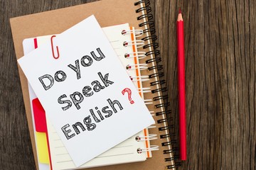 Do you speak english, Text message on white paper with notebook on wooden table, top view. business concept