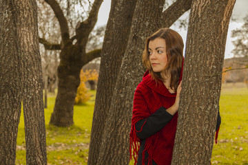 Side way portrait woman wearing red wool poncho. Nature autumn o