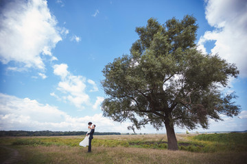 Fototapeta premium Bride and groom hugging near tree