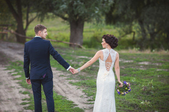 Newlyweds couple holding hands and walking outdoor after their wedding ceremony
