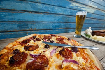 Italian pizza served with glass of beer on wooden plank
