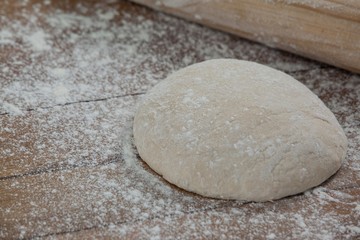 Rolling pin with pizza dough and flour on rolling board