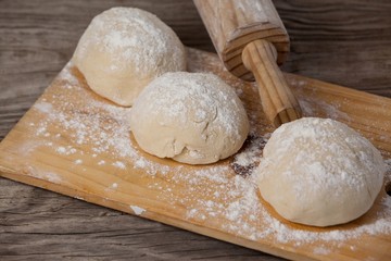 Rolling pin with pizza dough and flour on chopping board