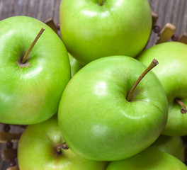 ripe green apples and apple slices on wooden gray background