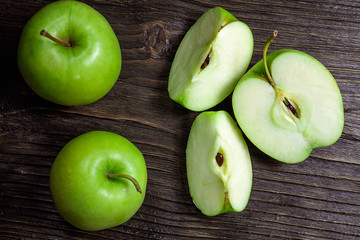 ripe green apples and apple slices on wooden gray background