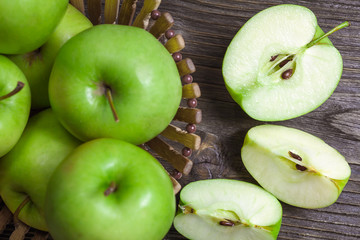 ripe green apples and apple slices on wooden gray background