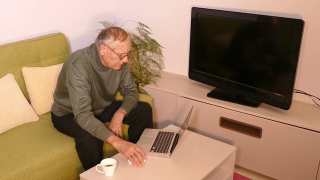 Old man talking on skype on laptop in the living room