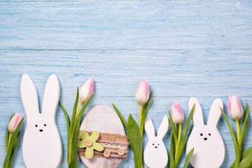 Easter background with white rabbits, pink tulips and easter egg, top view