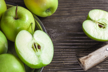 ripe green apples and apple slices on wooden gray background