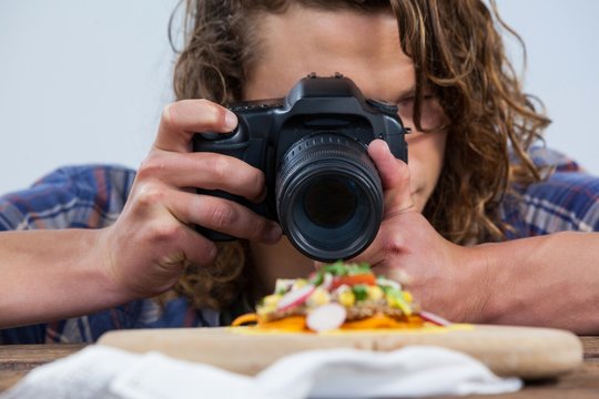 Photographer clicking a picture of food using digital camera 