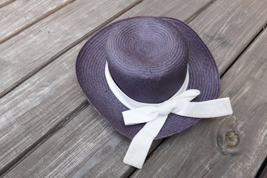 Straw hat with baw on wooden floor