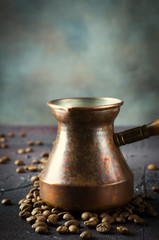 Old copper coffee pot and beans on dark rustic background