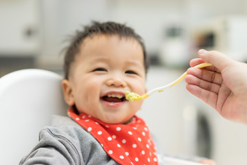 Asian baby boy eating blend food on a high chair © alice_photo