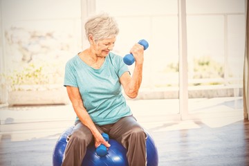 Smiling senior woman holding dumbbell