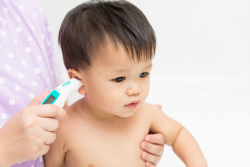 Mother uses the thermometer for Asian baby