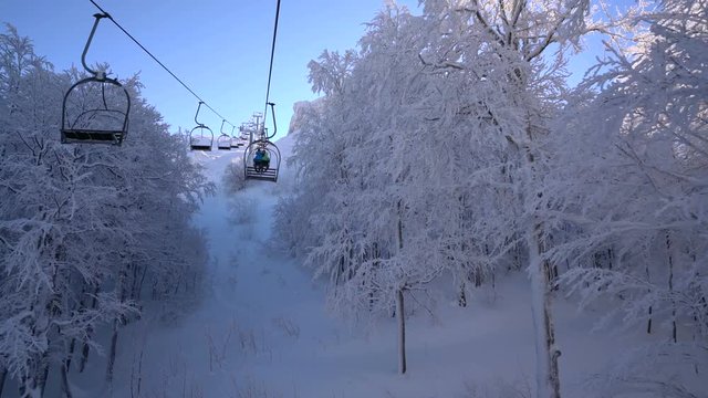 Snow forest and skiers on a ski lift pov