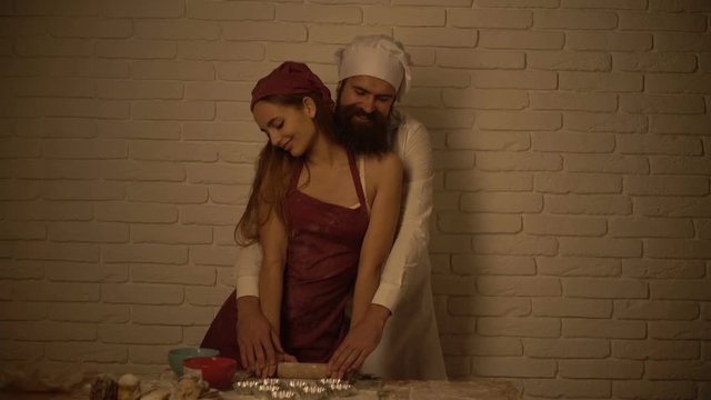 Sexy couple dressed as chefs cook in the kitchen. Husband and wife make cookies during the honeymoon