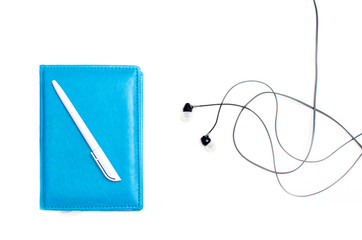Blue notebook with white ballpoint pen. Black little headphones. Isolated on white background.