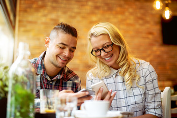 Couple at cafe bar looking at smart phones.