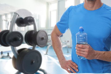 Sport fitness man drinking water after workout in gym