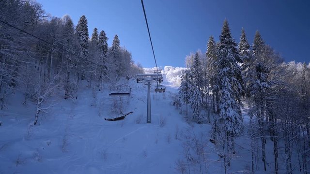 Snow forest and skiers on a ski lift pov