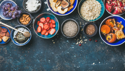 Ingredients for healthy breakfast over dark blue background, top view, copy space. Fresh and dried fruit, chia seeds, oatmeal, nuts, honey. Clean eating, vegan, healthy food, detox, dieting concept