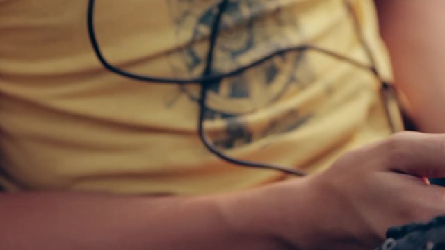 A teenage boy sitting in a park listening to music. Boy with headphones outdoors