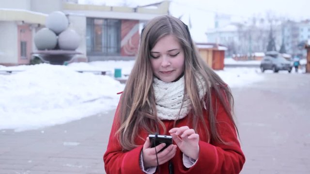 Plump girl choose music at winter street