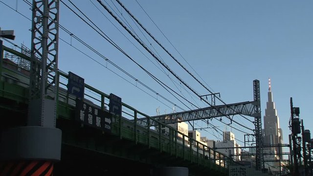Trains passing by from Shinjuku station with the NTT Docomo Yoyogi Building at the background.