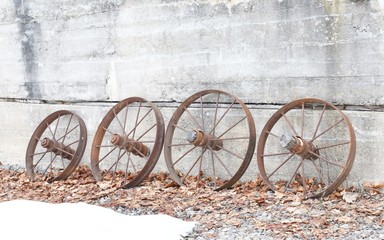 Metal wagon wheel spokes leaning against a concrete wall.