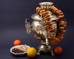 Russian samovar old silver on dark background with bagels lemon sweets tangerines
